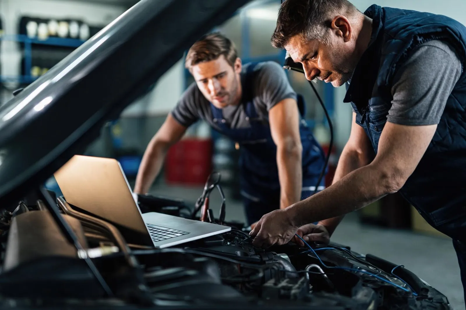 Fahrzeugdiagnose mit Laptop am Motorraum