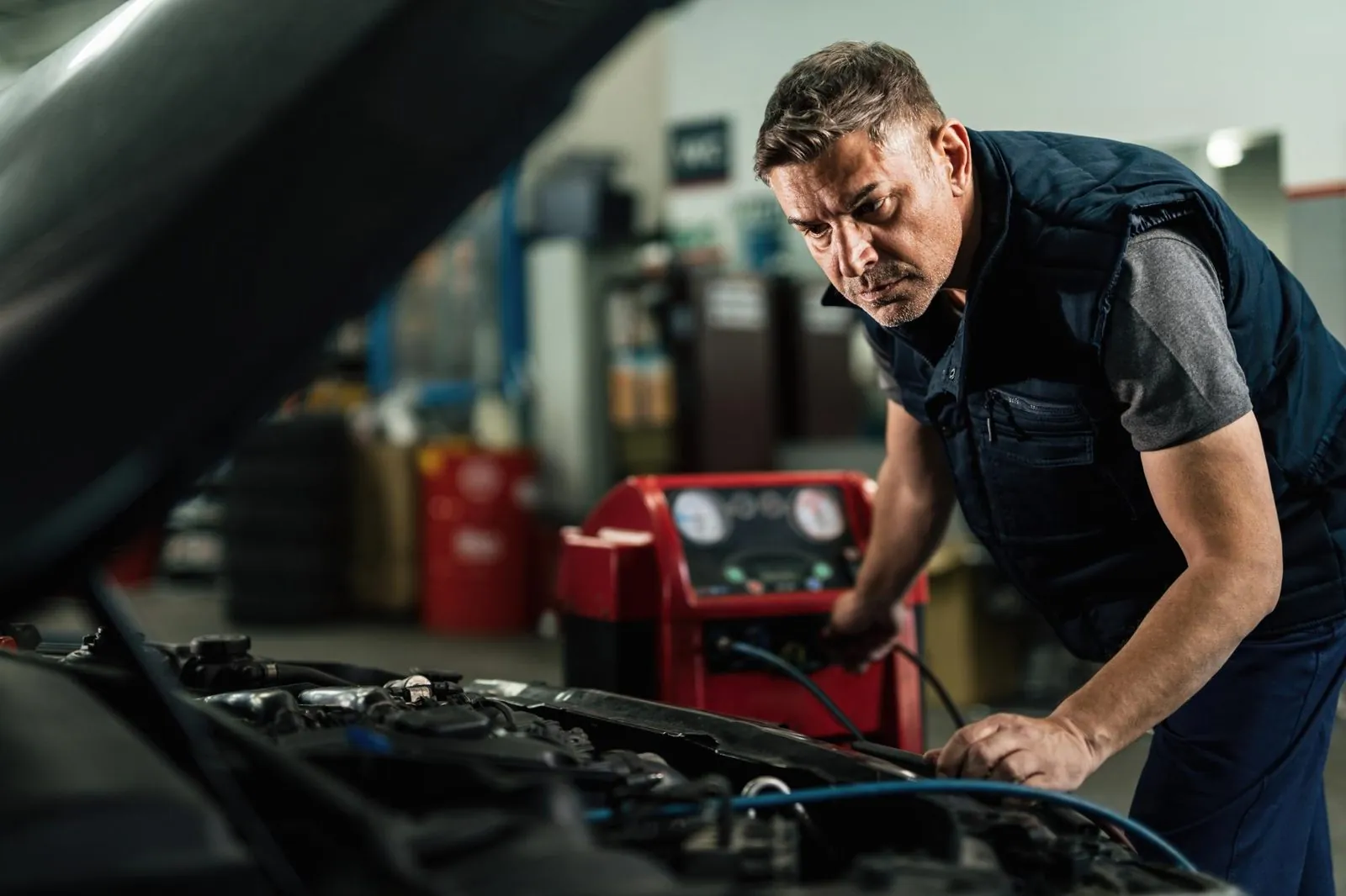 Mechaniker schließt das Klimaservicegerät an die Klimaanlage eines Autos an