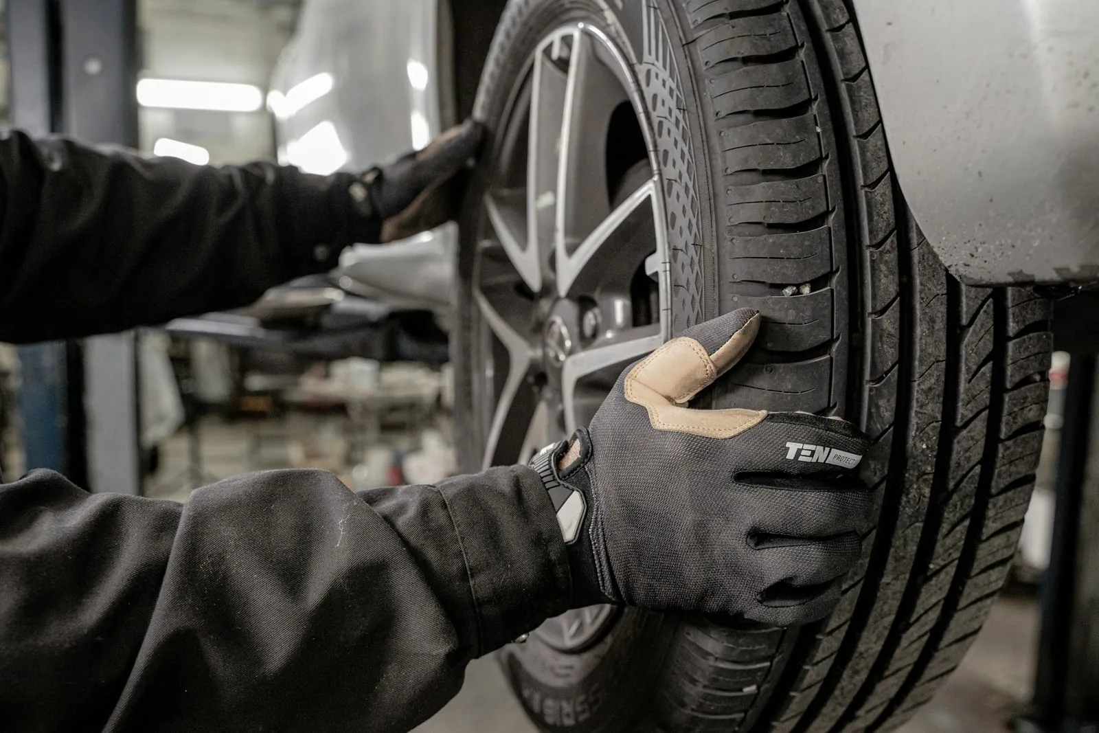 Mechaniker prüft einen Reifen am Auto auf der Hebebühne